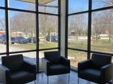 three chairs sitting in front of floor to ceiling windows with blue skies showing through
